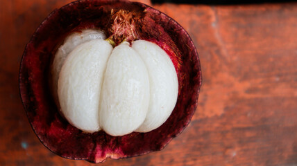 Ripe mangosteen fruit , revealing its juicy white segments inside the dark purple rind.