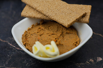 Close-up of a white plate with liver pate and slices of butter, bread on top of it on a dark background with space for text. The concept of snacks, healthy food, diet. High quality photo