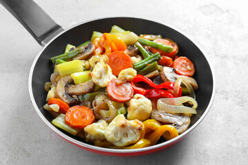 Different vegetables and mushrooms in frying pan on grey table, closeup
