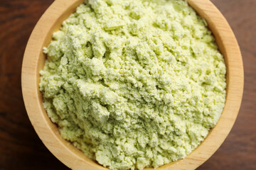 Dry wasabi powder in bowl on wooden table, top view