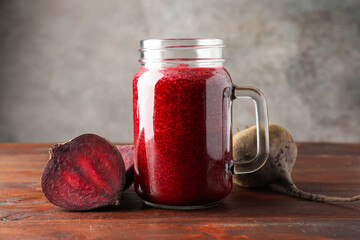 Fresh beetroot smoothie in mason jar and vegetables on wooden table, closeup