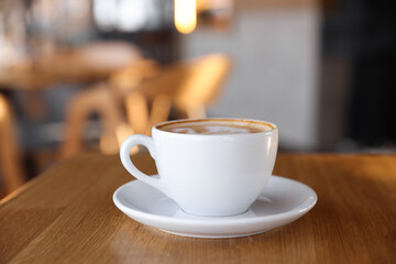 Cup of aromatic coffee on wooden table in cafe, closeup