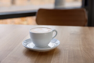 Cup of aromatic coffee on wooden table in cafe