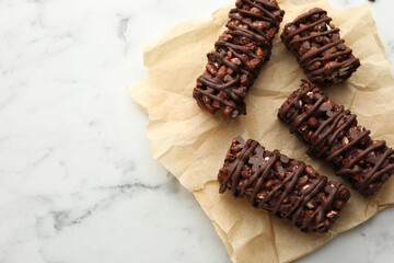 Delicious chocolate puffed rice bars on white marble table, top view. Space for text