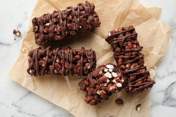 Delicious chocolate puffed rice bars on white marble table, top view