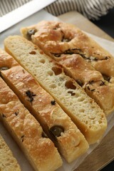 Slices of delicious focaccia bread with olives, thyme and salt on table, closeup