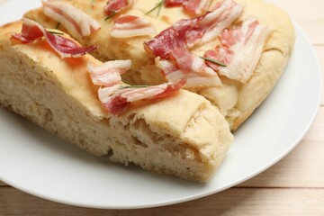 Pieces of delicious focaccia bread with bacon and rosemary on wooden table, closeup