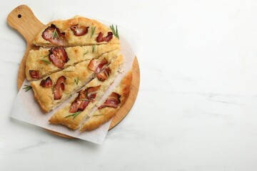Slices of delicious focaccia bread with bacon and rosemary on white marble table, top view. Space for text