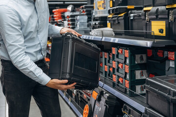 Toolbox in hands. Detailed close up view of man's hand in the hardware store