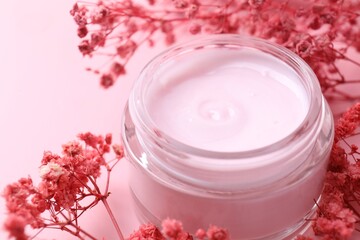 Jar of moisturizing cream and gypsophila flowers on pink background, closeup
