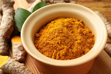 Turmeric powder in bowl on table, closeup