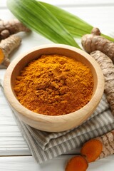 Aromatic turmeric powder, fresh roots and leaves on white wooden table, closeup