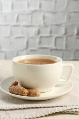 Aromatic turmeric tea and rhizomes on white textured table. Space for text