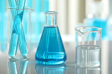 Laboratory glassware with liquid on mirror surface indoors, closeup