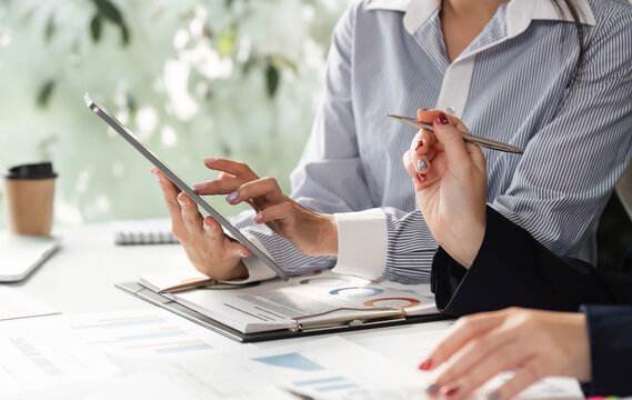 Professional team analyzing financial reports and data in a modern office setting, discussing strategies and insights. - Powered by Adobe