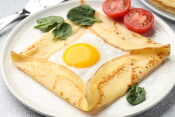 Delicious crepe with egg, tomato and basil on table, closeup
