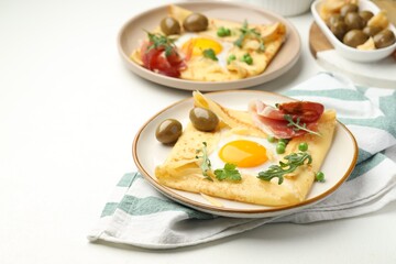 Delicious crepes with eggs and bacon served on white table, closeup. Space for text
