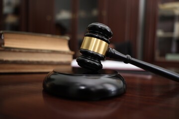 Judge workplace with gavel and books indoors, closeup