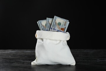 Dollar banknotes in burlap sack on grey table