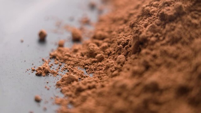 Instant cocoa powder particles falling in slow motion. Aromatic drink soluble ingredient. Macro shot. Rotation