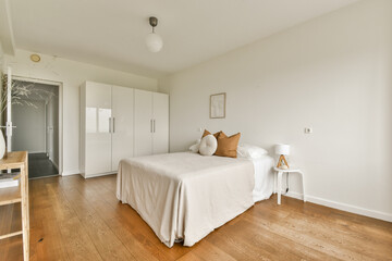 A serene and minimalist bedroom featuring a wooden floor, simple furniture, and soft color palette, enhancing tranquility and elegance.