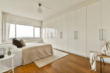 A sleek and contemporary bedroom featuring a light color palette, large wardrobe, and elegant furnishings that create a serene atmosphere.