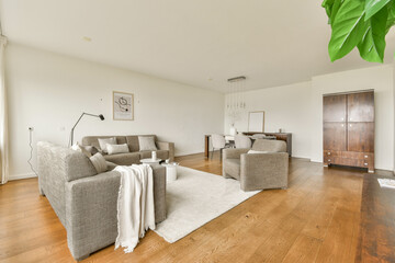 Stylish living room featuring neutral furniture, warm wooden floors, and ample natural light, creating a cozy yet modern atmosphere for relaxation and socializing.