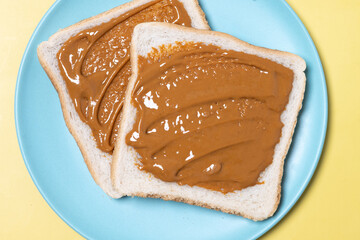 Bread toast with peanut butter cream on yellow background