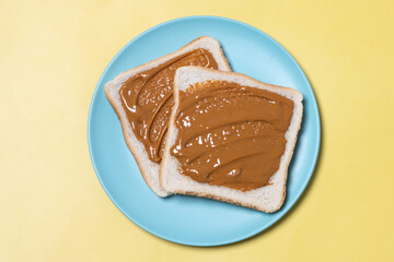 Bread toast with peanut butter cream on yellow background