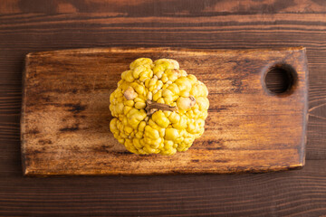decorative orange Pumpkin with tumors on cutting board on brown wooden, top view, close up