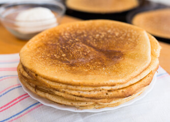 Freshly baked hot cereal pancakes on plate and pans during cooking