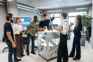 Employees are together. People are in the office by the 3d printer