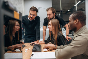 By computer. Designer team are together in the office