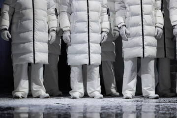 Closeup of men in white puffer coats on stage