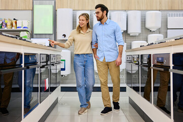 A couple joyfully shops for kitchen appliances in a modern store, enjoying their time