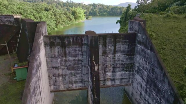 Hatillo Dam, concrete structure surrounded by lush greenery, Cotui in Dominican Republic. Aerial drone ascending