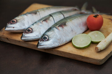 Some Fresh Mackerel Fish with slice of lemon, red tomato and lemon grass On Wooden Chopping Board, prepare cooking seafood