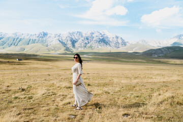 Fototapeta premium view of beautiful woman in black outfit holding necklace in a beautiful mountains land