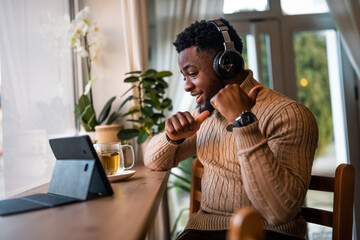 Freelancer using digital tablet to communicate online. He is sitting in bar and having video call.