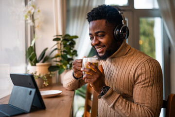 Freelancer using digital and having video call in bar. He is drinking tea.