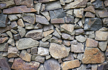 Photo of a stone wall. A wall made of stones. Natural material used to build the wall. Texture, stone, stony lining.