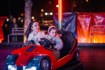 Mother and daughter enjoying bumper car ride at amusement park