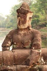 One of the many stone giants lined up on the bridge leading to the Prasat Preah Khan Temple,...