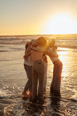 Friends embracing at sunset on beach: sharing a tender moment of togetherness