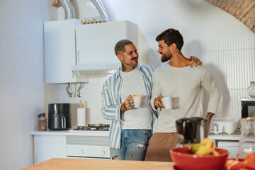 Two men embracing and smiling over coffee in a modern kitchen