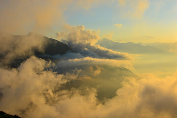 Golden Sunset Over Majestic Mountains: A Serene Cloud-Kissed Landscape