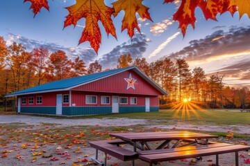 A red barn with a star on the roof sits in a field of autumn leaves