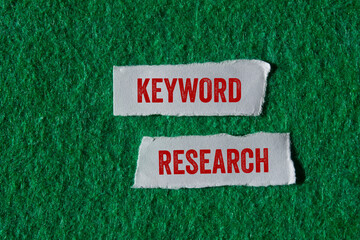 Keyword research message written on ripped torn paper pieces on green background. Conceptual...
