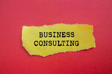 Business consulting message written on ripped torn yellow paper on red background. Conceptual business consulting symbol. Copy space.