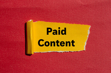 Paid content message written on ripped torn yellow paper on red background. Conceptual paid content symbol. Copy space.